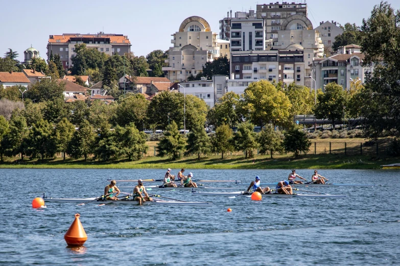 rowing in a lake next to a city with a large building on the shore