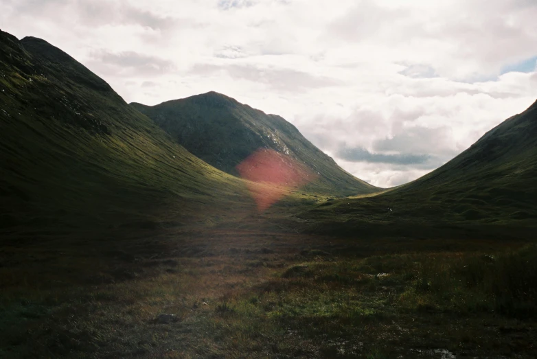 a grassy area with mountains on the far side of it