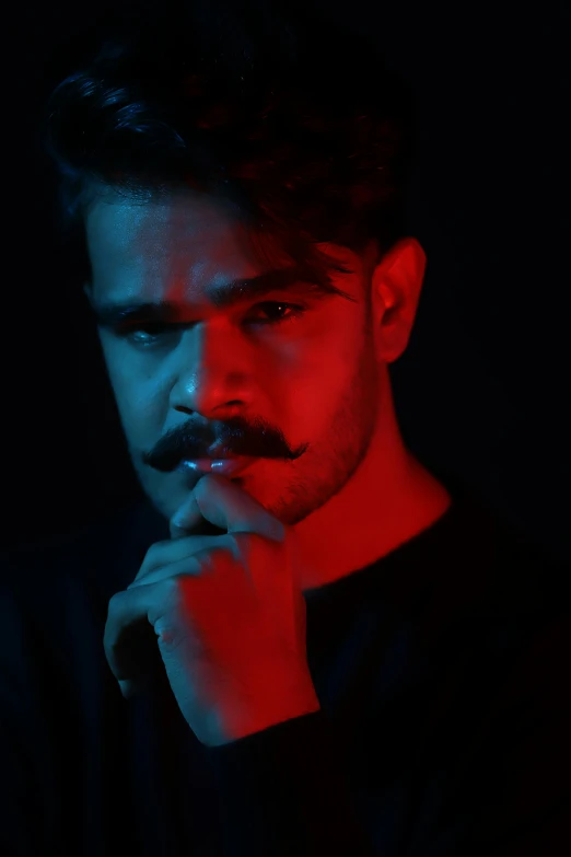 a young man posing for a pograph with a red light behind his