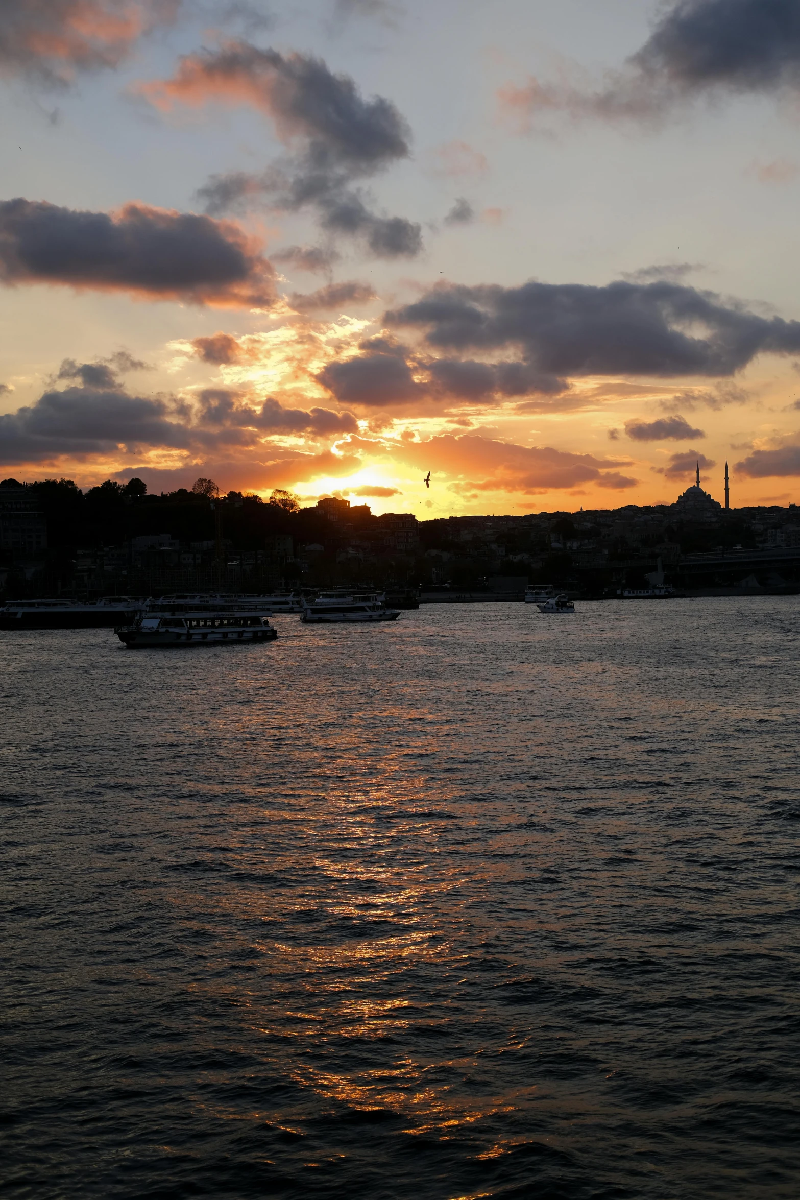 several boats are floating in the water at dusk