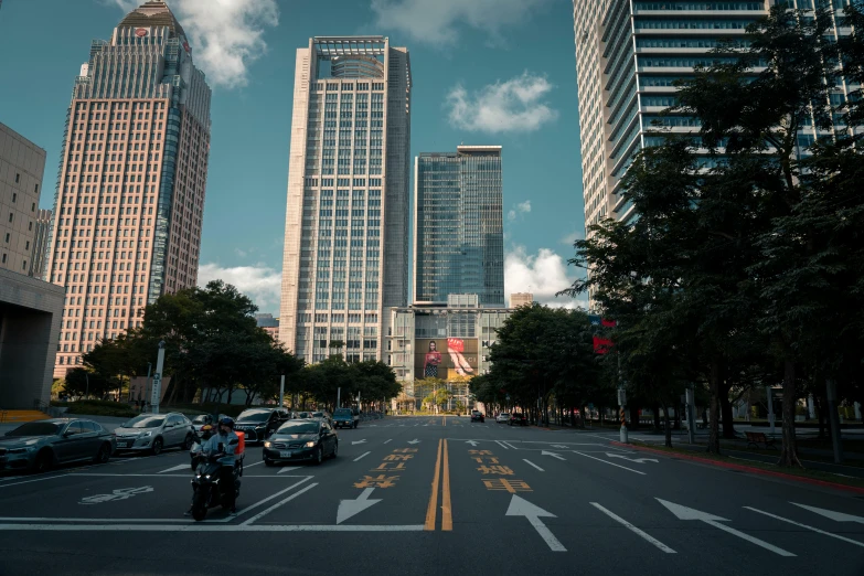 cars are driving down a city street with tall buildings