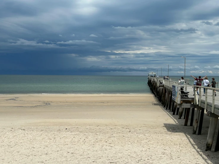 people are walking towards the ocean on a boardwalk