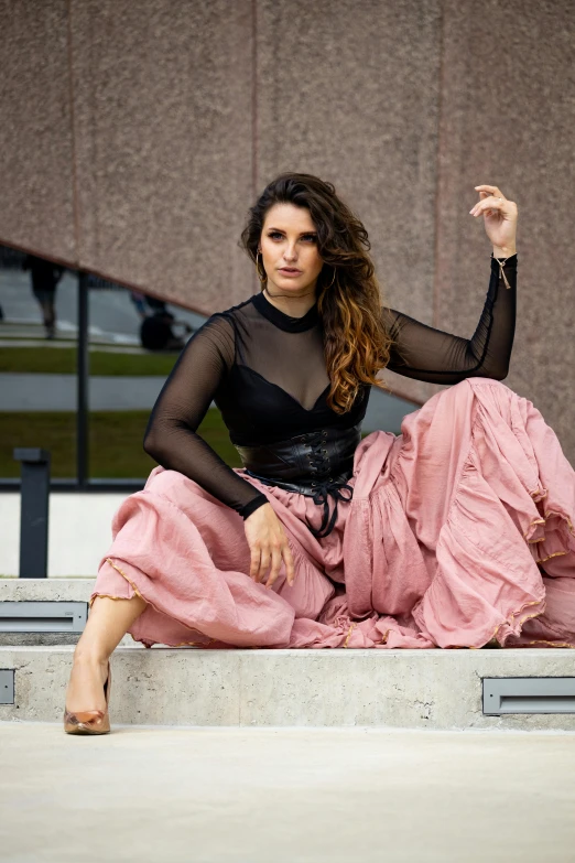 a woman in a black and pink dress and heels sitting on a step