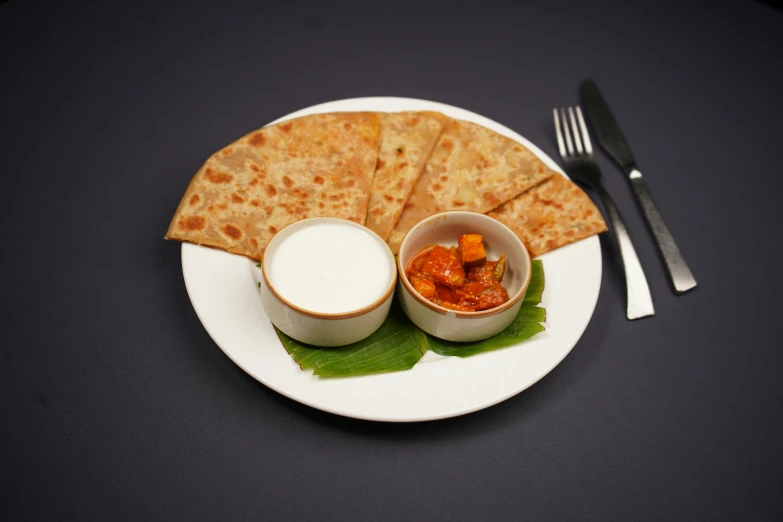 some pita breads on a white plate with sauce