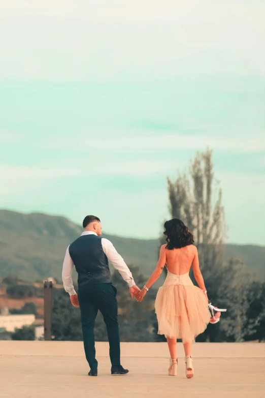 a newly married couple holding hands with the mountains behind them