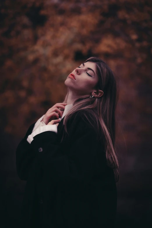 woman in black jacket leaning against wall with eyes closed