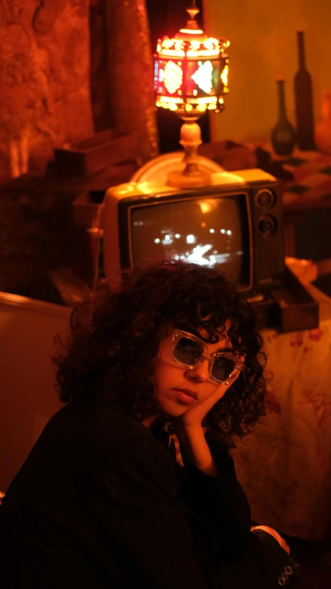 a woman with long curly hair in front of an old - fashioned tv