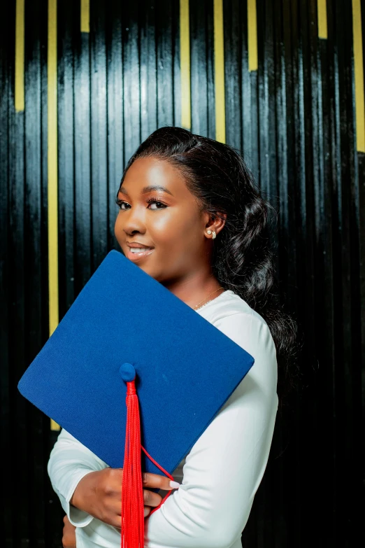 the beautiful black woman is holding her blue and red graduation diploma