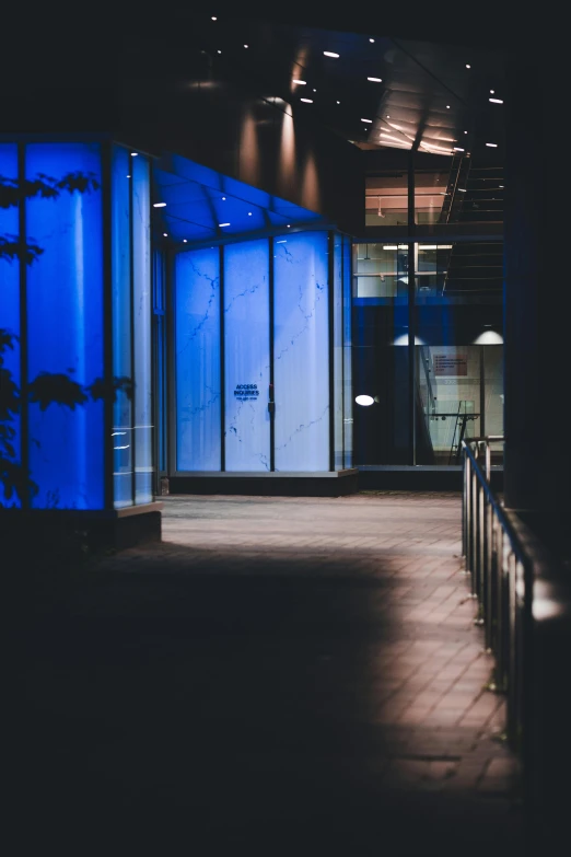 an illuminated blue building with multiple stories in front