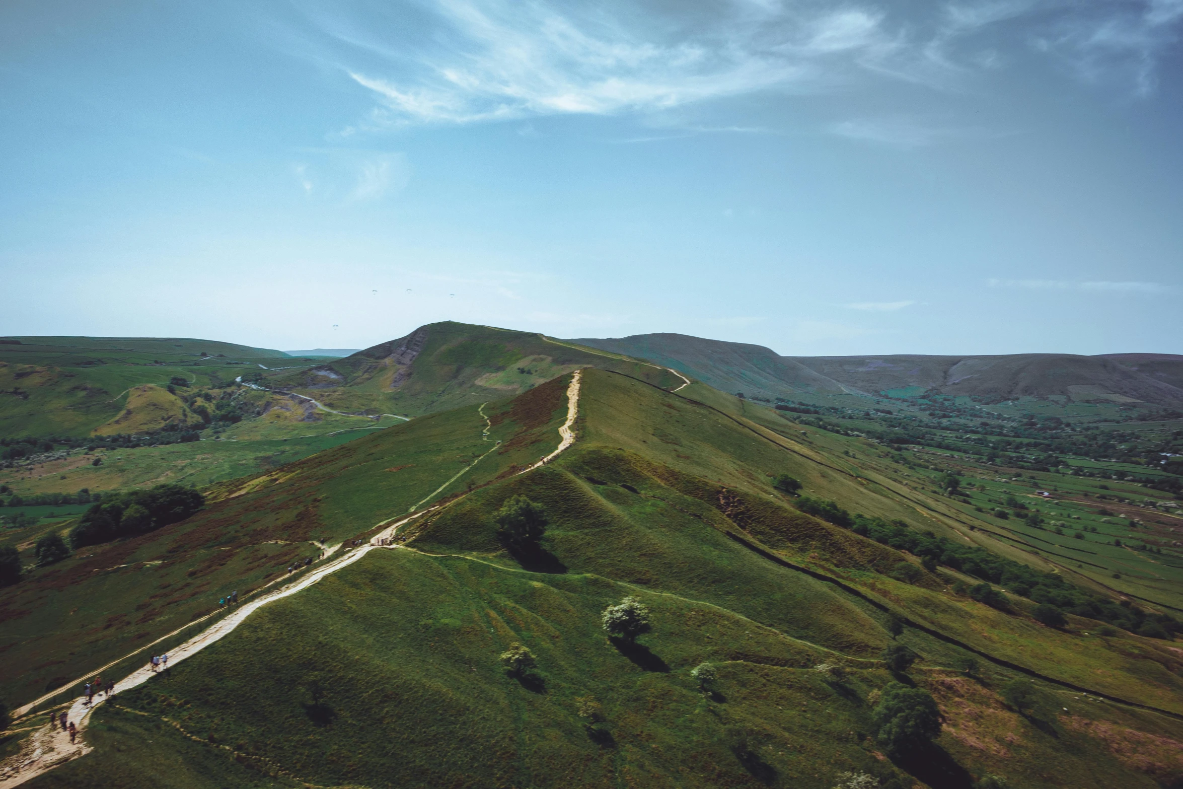 a lush green hillside with some dirt roads on it