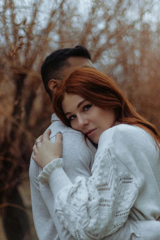 a man and a woman hug in the woods