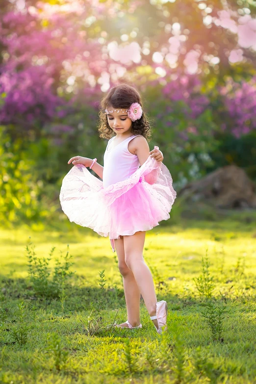 a  in a pink dress is standing in the grass