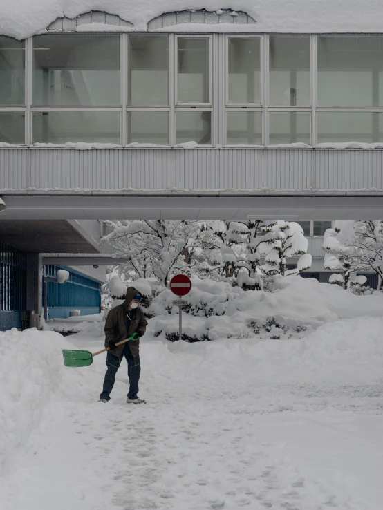 a person shoveling through the snow in front of a building