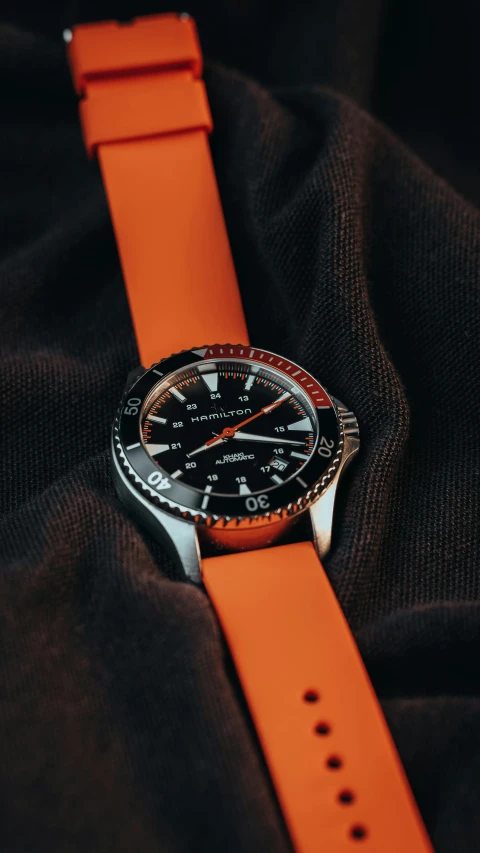 a watch on some black cloth covered in orange
