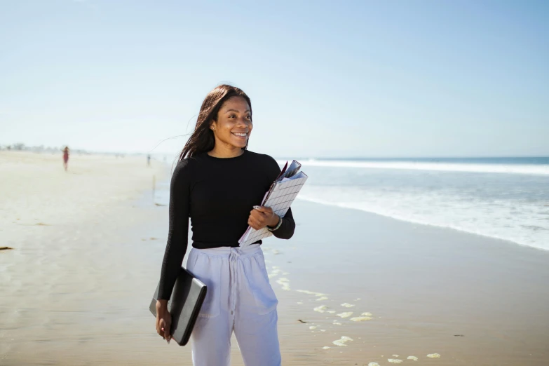a girl on the beach holding some papers