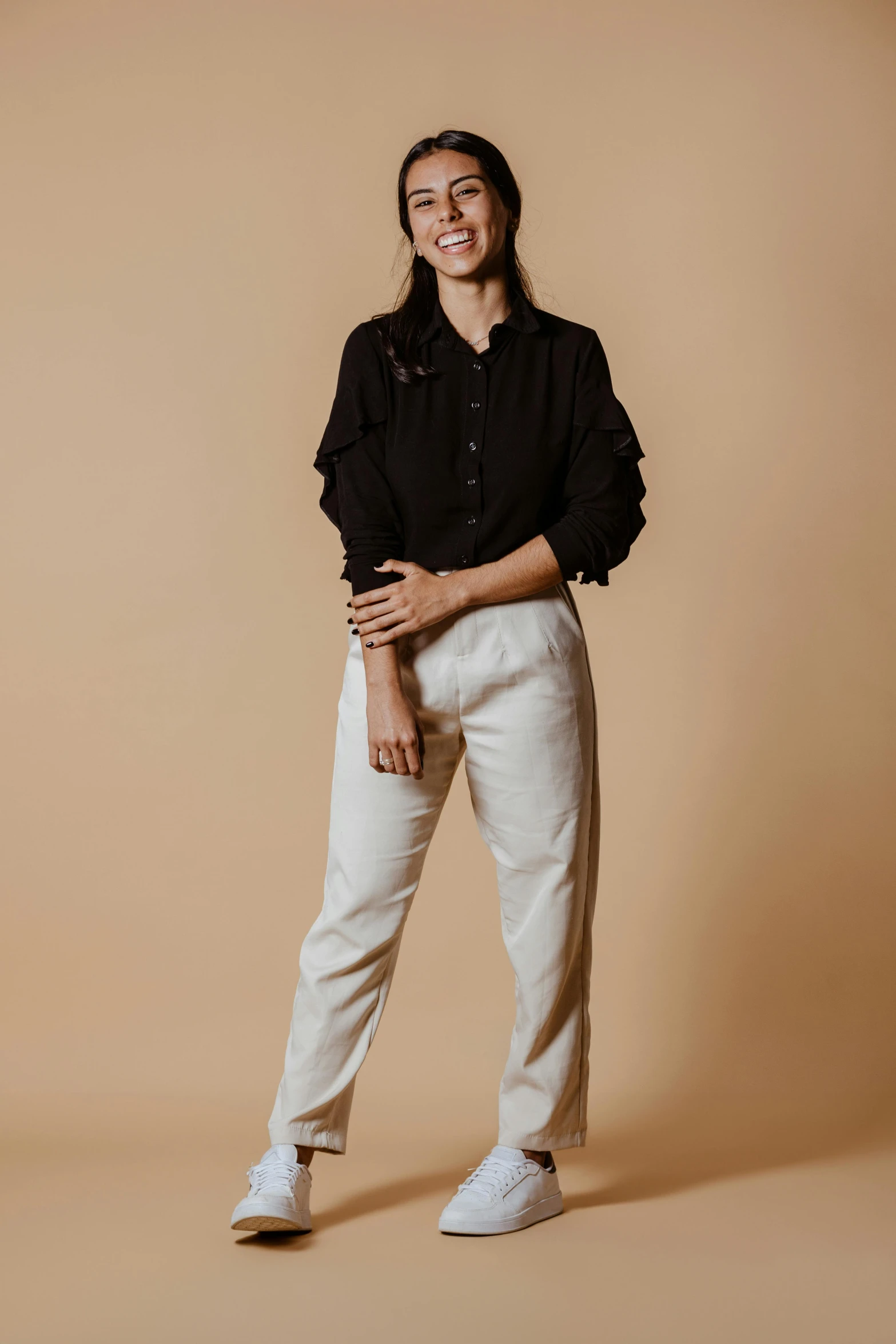 a woman poses for the camera in a black shirt and white pants