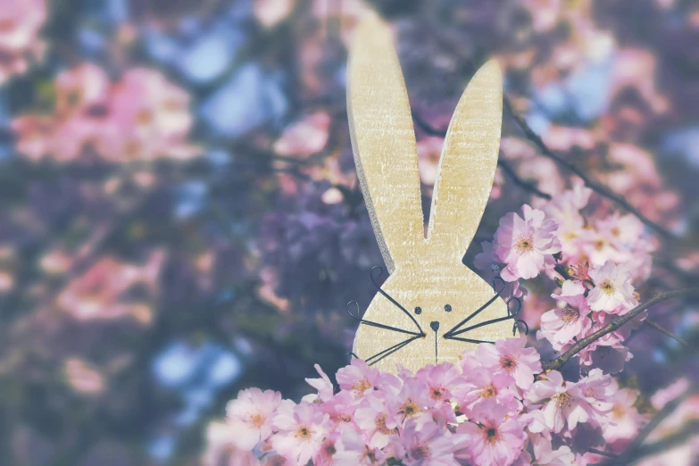 a wooden toy rabbit on a tree filled with flowers