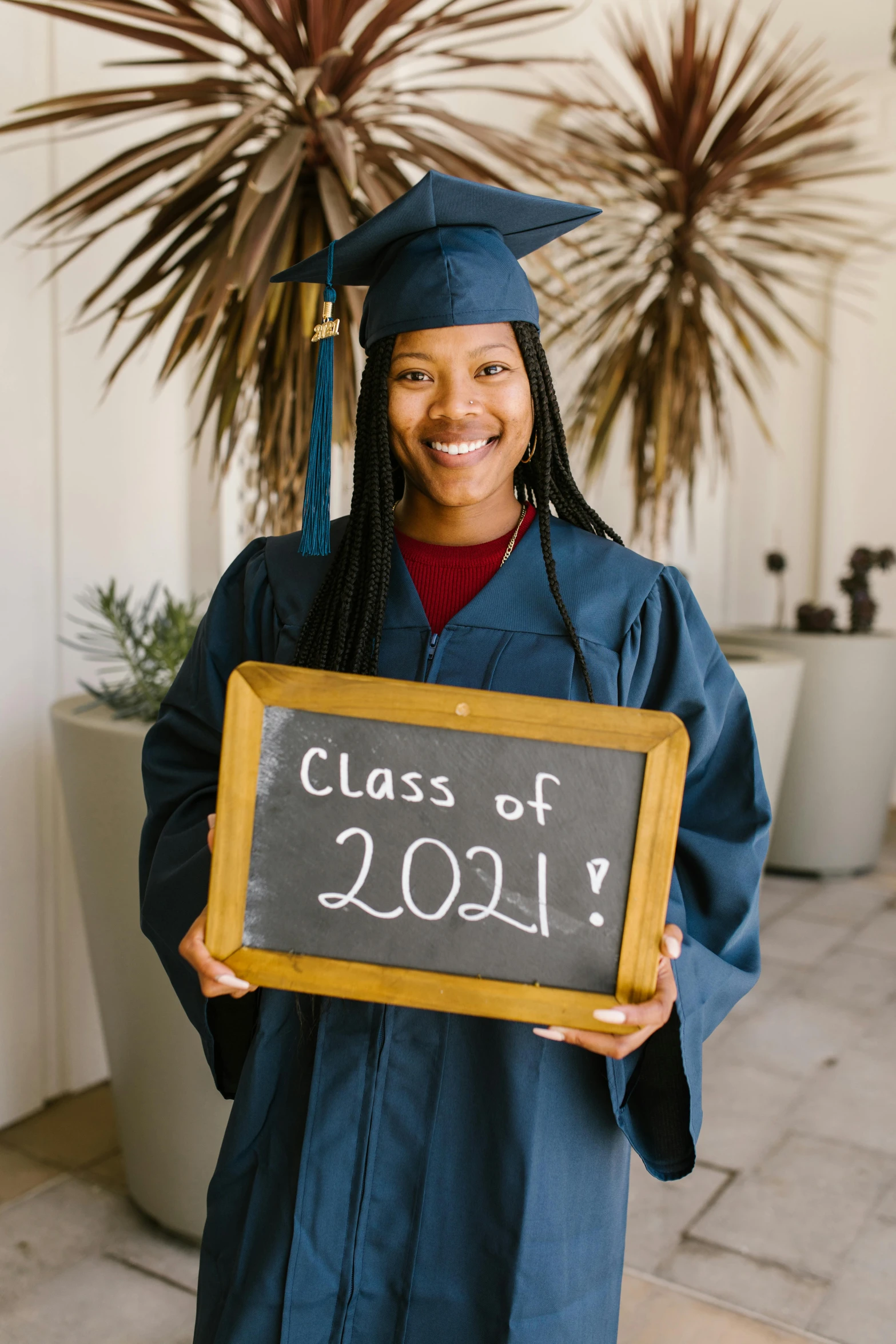 smiling graduate in gown holding graduation sign