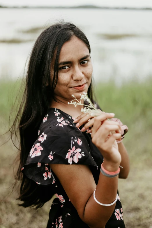 a young woman in a black and pink dress poses in a field