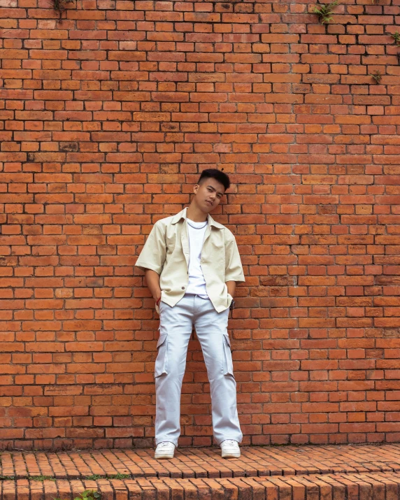 a young man standing in front of a brick wall