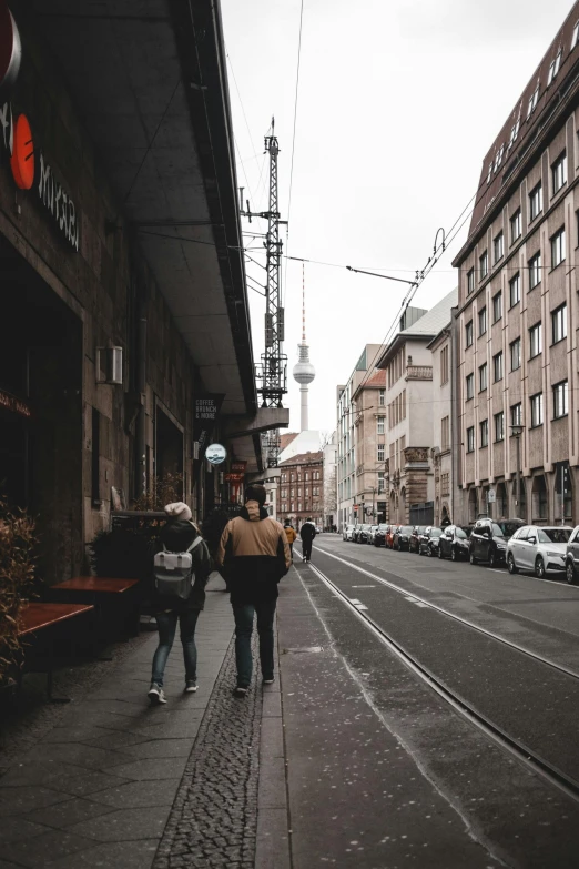 pedestrians walk down the sidewalk next to a tall building