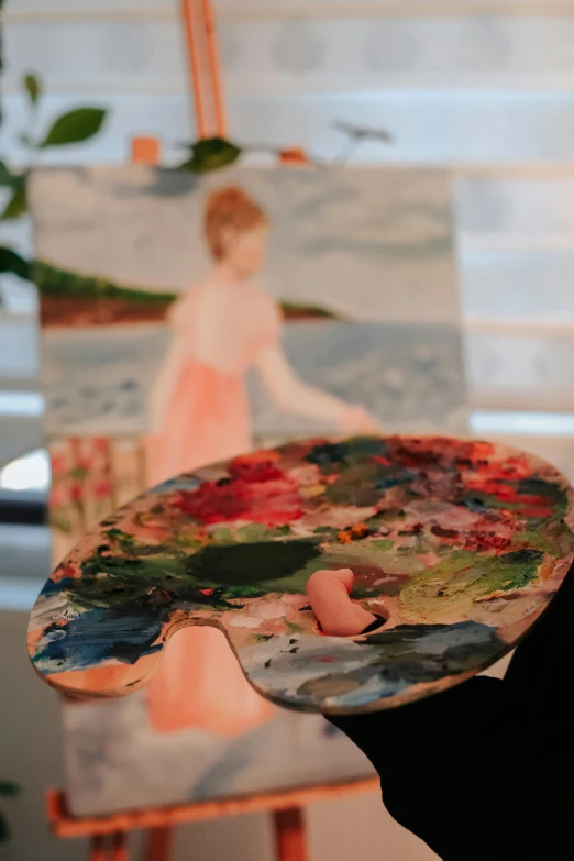 a person holding an art piece with paintings on them