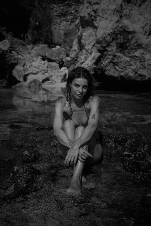 an  woman sitting in the water of a stream