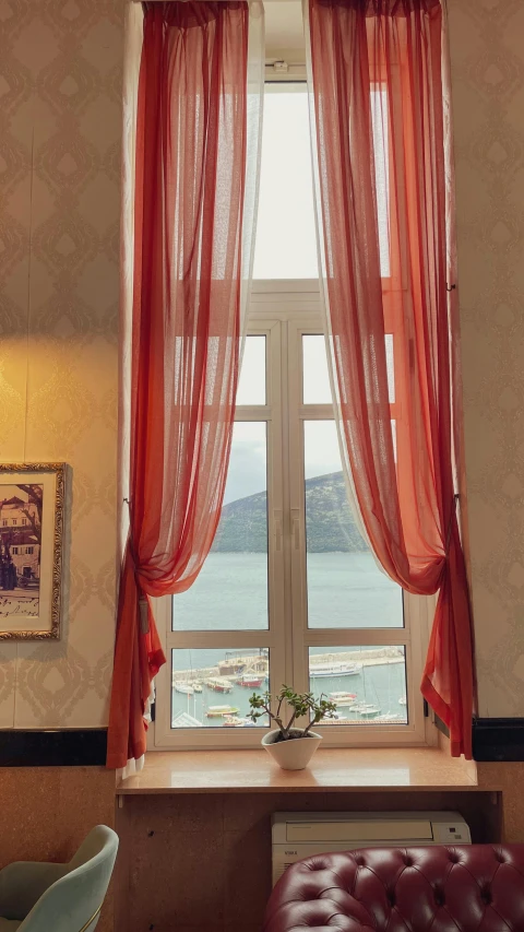 a window with sheer curtains and pink curtains