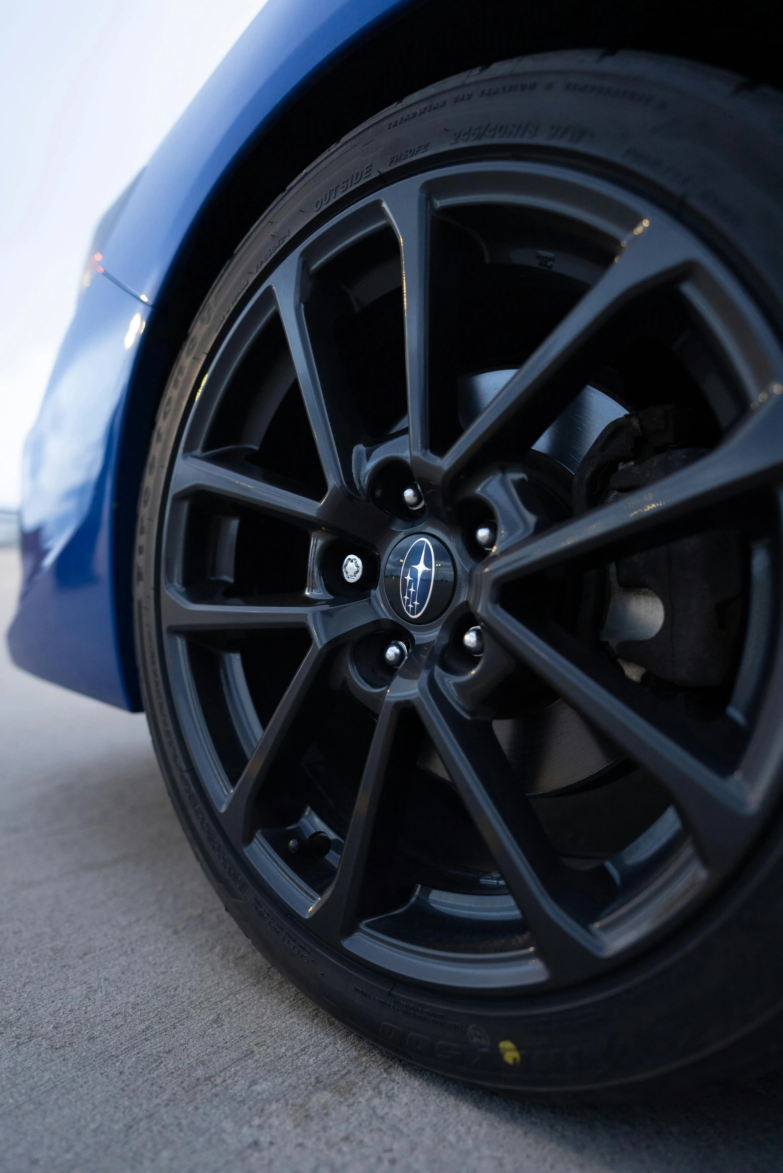 a car with black rims and grey wheel on a sidewalk