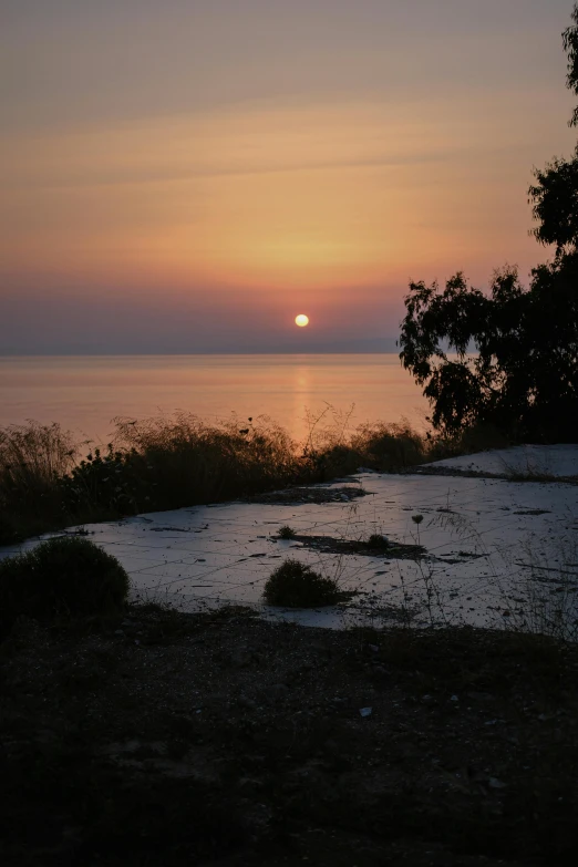 sunset over a water filled bay near small wooded area