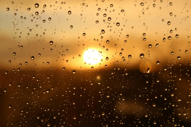 water drops on the window outside of a sun set