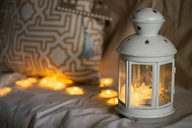 a white lantern on a bed with candles