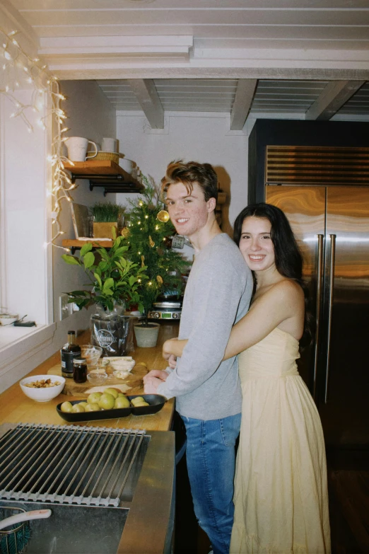 a young man and woman standing in the kitchen, preparing food