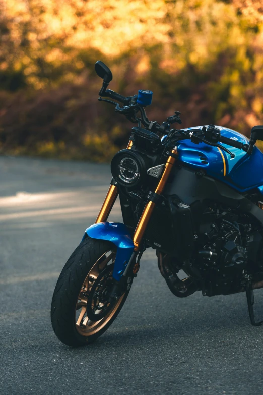 a blue motorcycle on a street with trees in the background