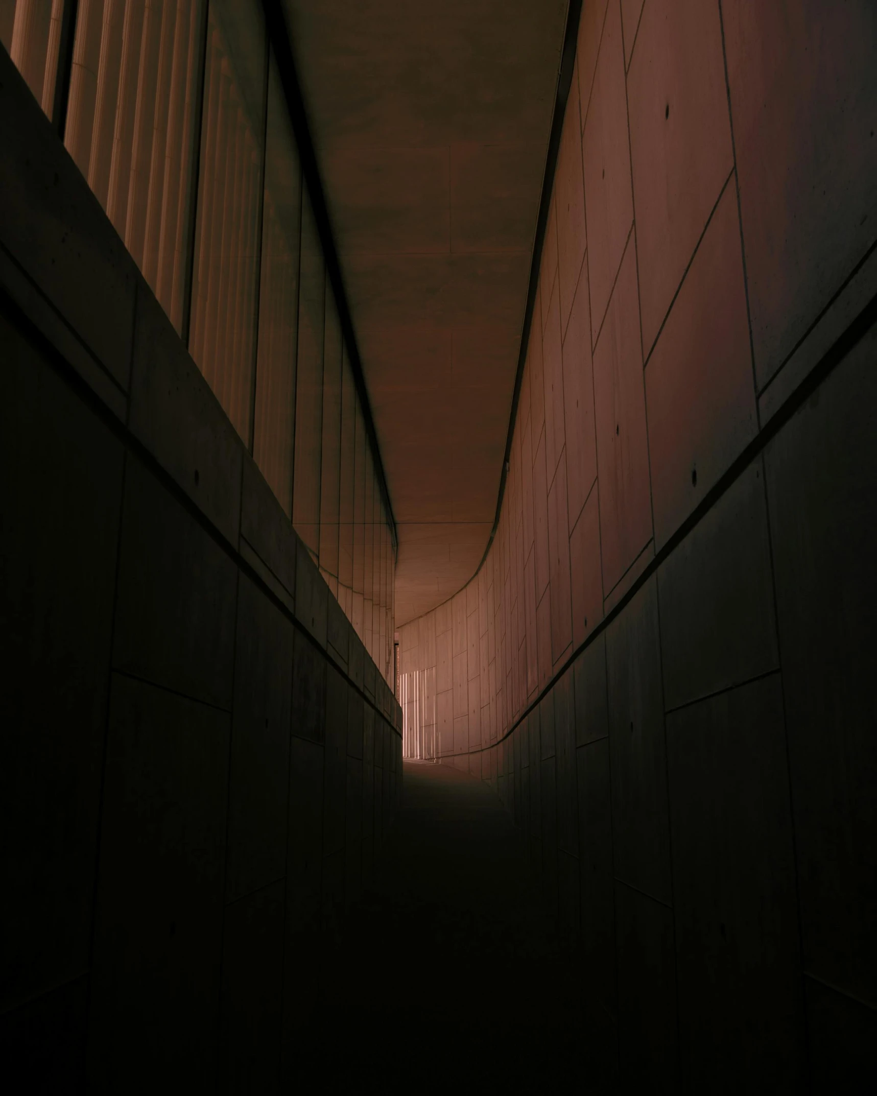 a dark tunnel with lights shining down between two walls