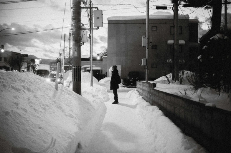 a woman walks down a street with a bunch of snow on it