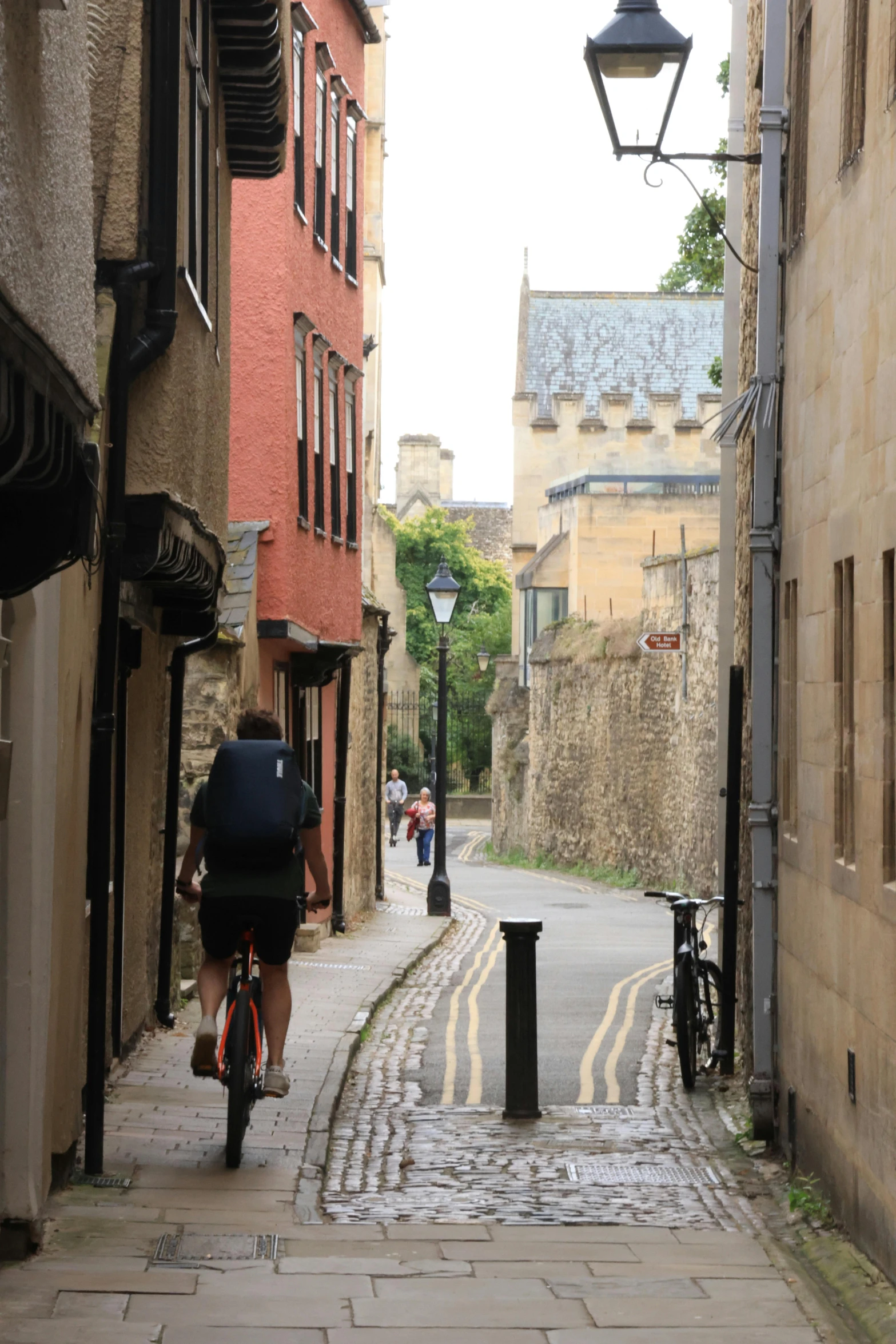 man walking down the narrow alley way with a bike