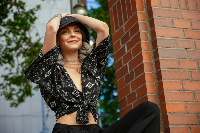 a woman is sitting against a wall posing for the camera