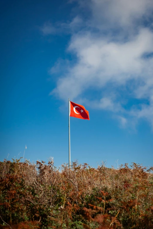 there is a red and white flag on the top of a hill