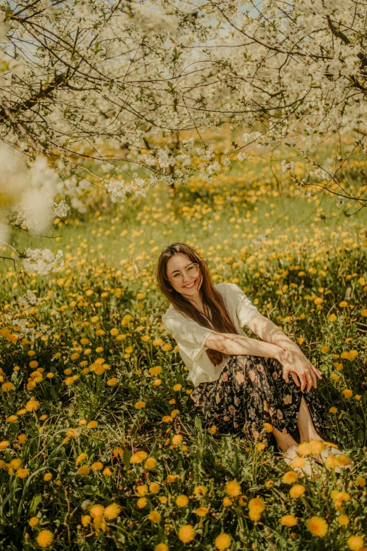 a woman sitting on the grass next to some flowers