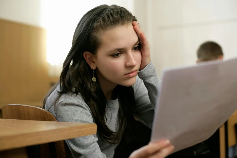 a girl in grey sweater using laptop computer in a classroom