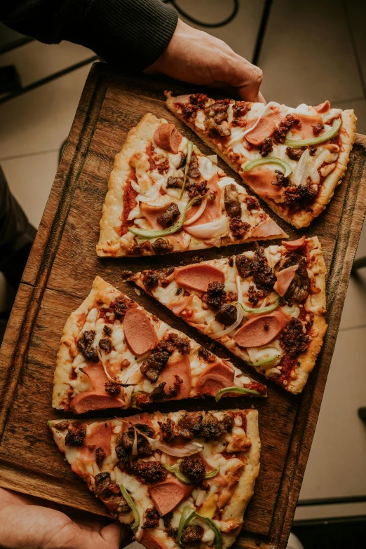 a person holding up slices of pizza with many toppings