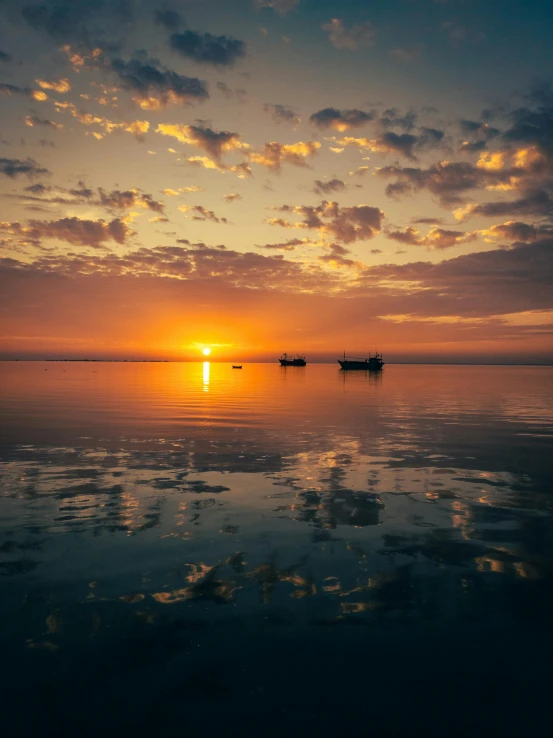 the sun is rising over the horizon as three small boats are in the water