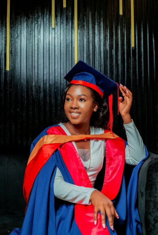 a young woman in her graduation gown sits in front of a black background