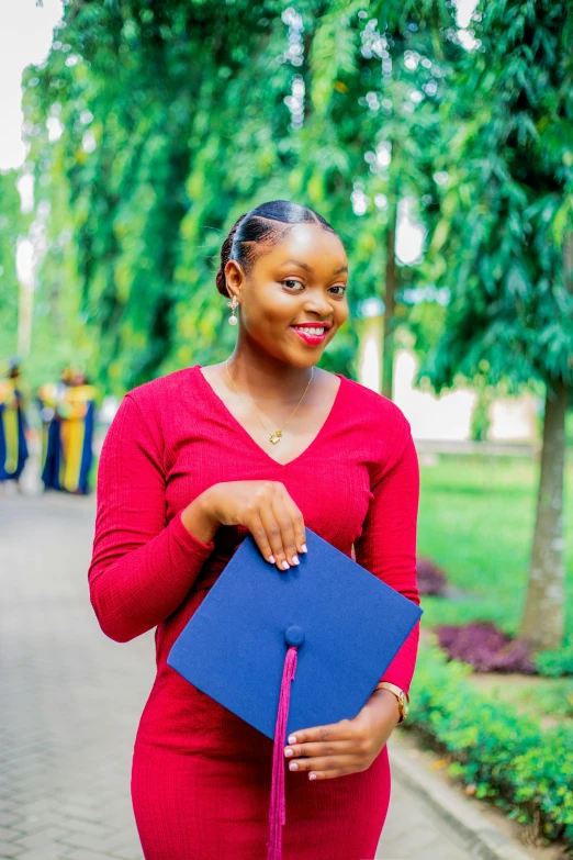 a woman holding a blue graduation cap with pink tassel