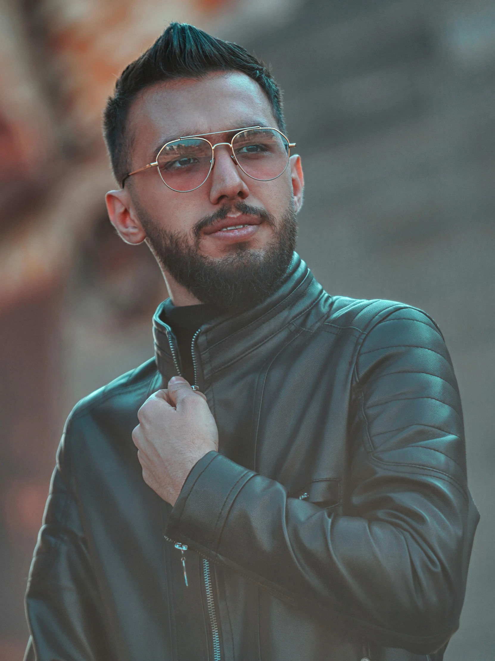 a bearded man wearing leather with a jacket and eyeglasses