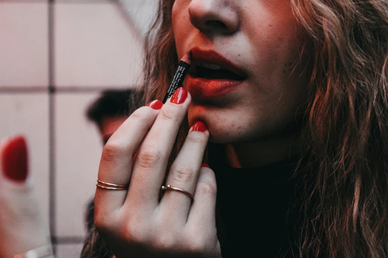 a woman with red fingernails holding a pen