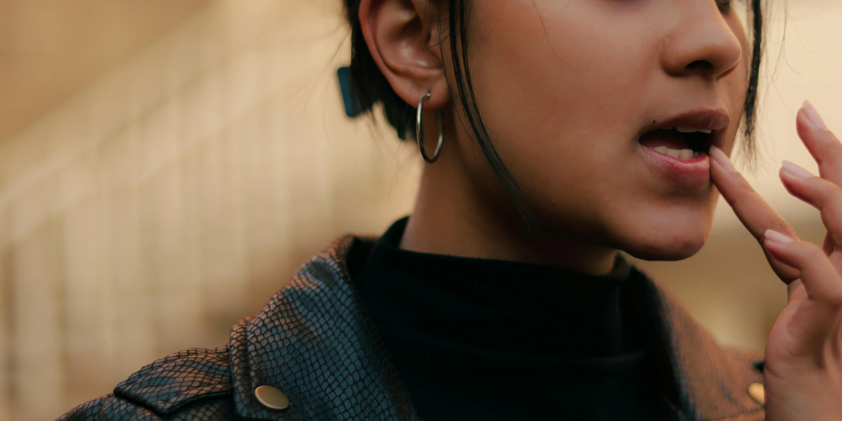 woman in black shirt and jacket holding cigarette and making silly face