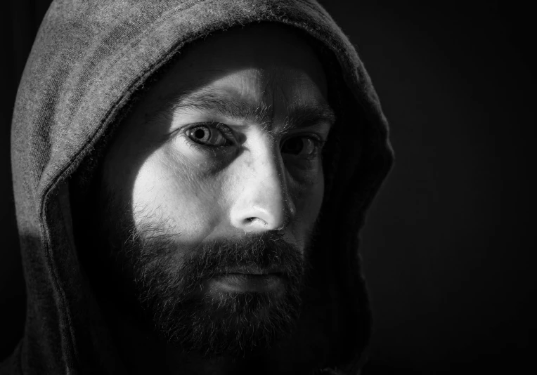a man with a hooded sweatshirt is shown in black and white