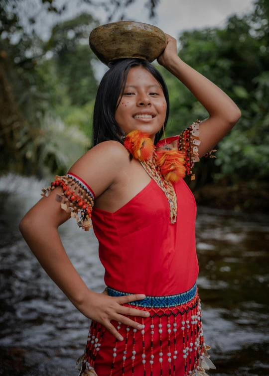 a woman in red holding a bowl on her head